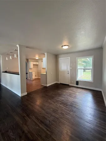 an empty room with wooden floor fan and windows