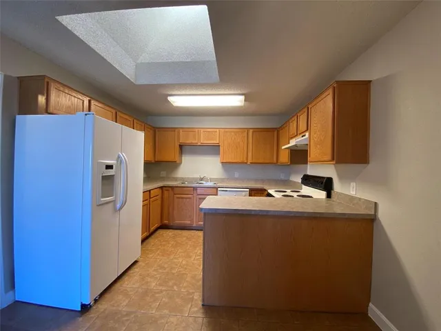 a kitchen with a refrigerator sink and wooden cabinets
