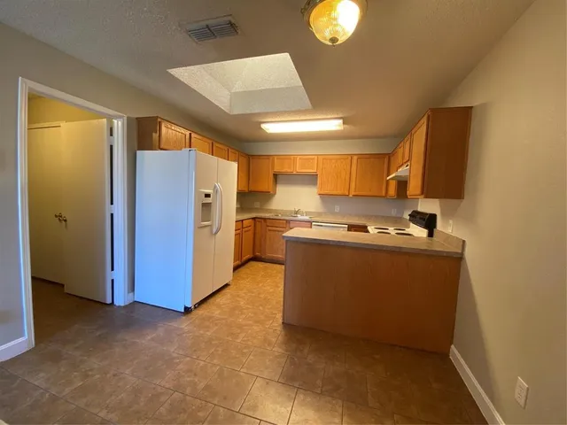 a room with stainless steel appliances kitchen island granite countertop a refrigerator and a stove top oven