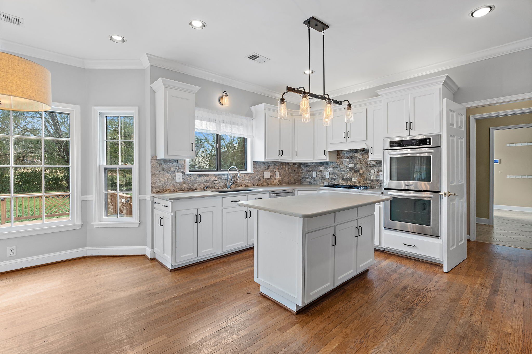 6916 Sunderland Circle Nashville, TN 37221 - Photo 14 of 43 a kitchen with stainless steel appliances granite countertop a stove a sink and white cabinets with wooden floors