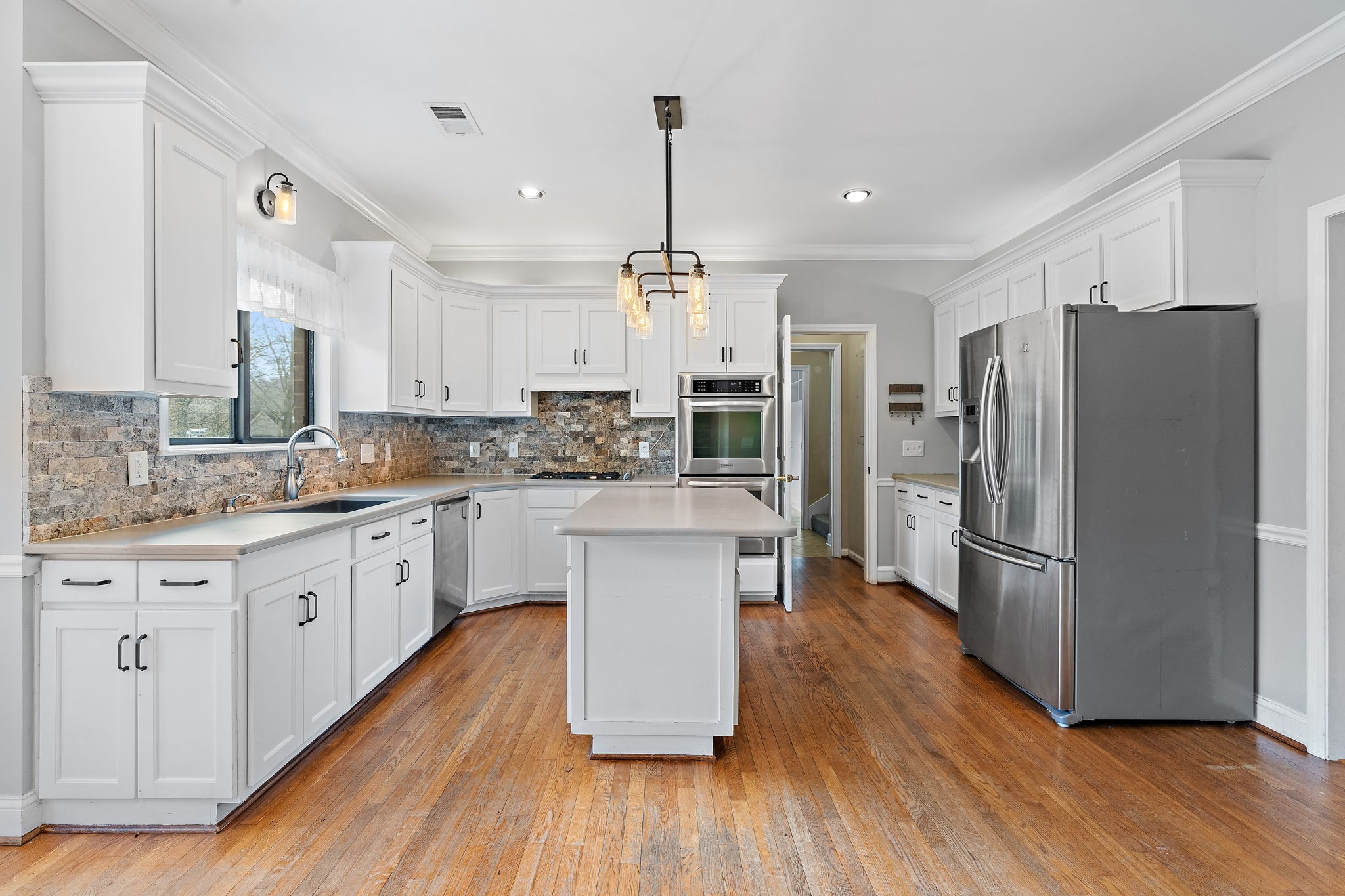 6916 Sunderland Circle Nashville, TN 37221 - Photo 15 of 43 a kitchen with kitchen island granite countertop a refrigerator a sink dishwasher a stove and white cabinets with wooden floor