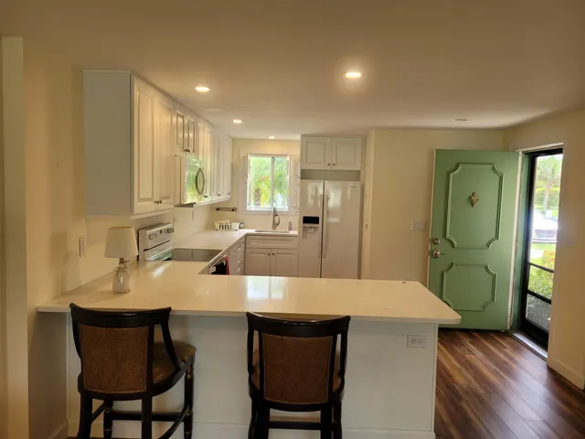 a large kitchen with lots of counter space a sink refrigerator dining table and chairs
