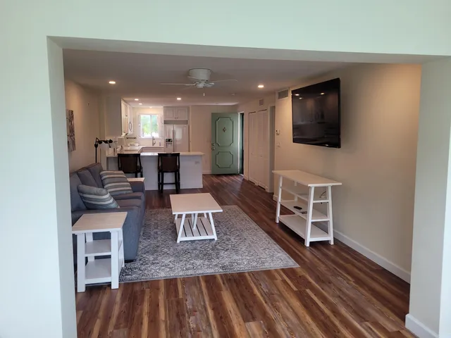 a living room with furniture a flat screen tv and kitchen view