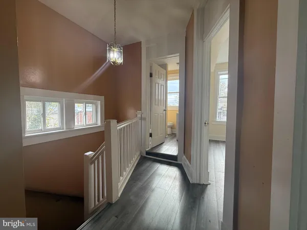 a view of an empty room with wooden floor and a ceiling fan