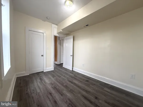 a view of an empty room with wooden floor and closet