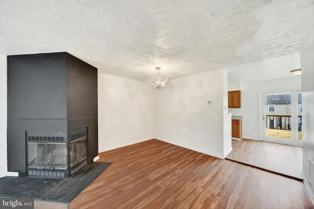 an empty room with wooden floor and kitchen view