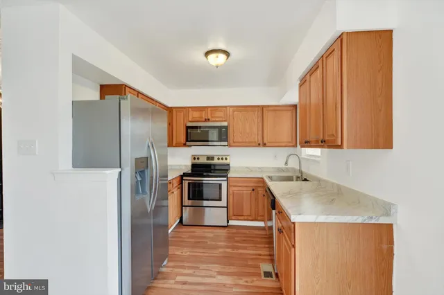 a kitchen with stainless steel appliances granite countertop a refrigerator a stove top oven a sink and dishwasher