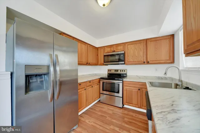 a kitchen with stainless steel appliances granite countertop a refrigerator a stove a sink and a microwave