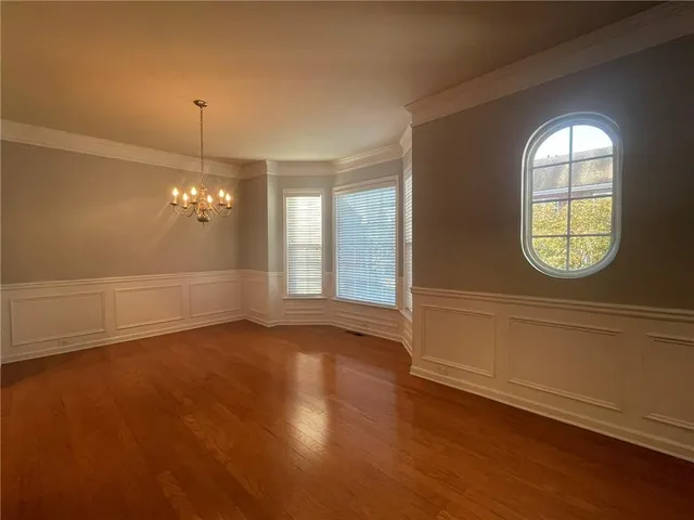 an empty room with wooden floor mirror and windows