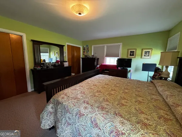 a bed sitting in a spacious bedroom next to a window and dresser