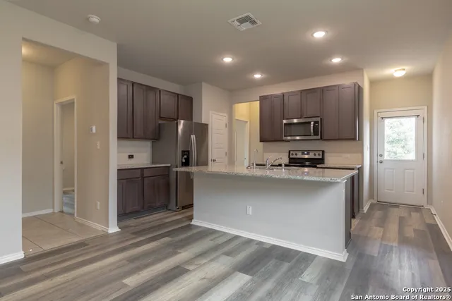 a kitchen with kitchen island granite countertop a refrigerator stove top oven and sink