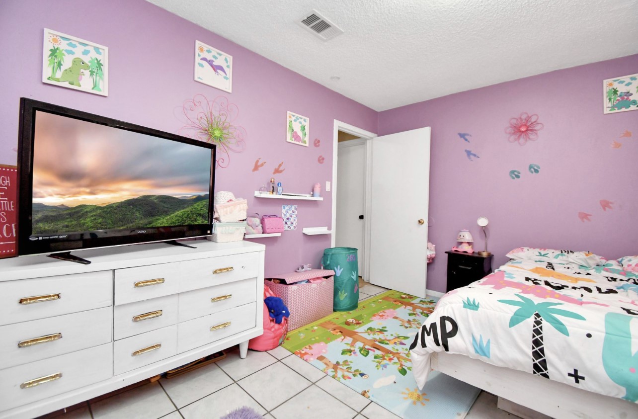 712 Meadowick Drive Baytown, TX 77521 - Photo 11 of 21 a bedroom with a bed and a flat screen tv