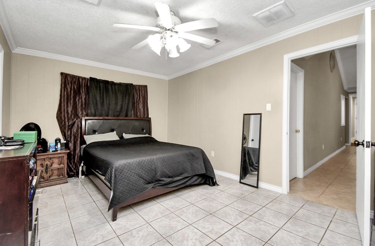 712 Meadowick Drive Baytown, TX 77521 - Photo 13 of 21 a bedroom with a bed and a chandelier