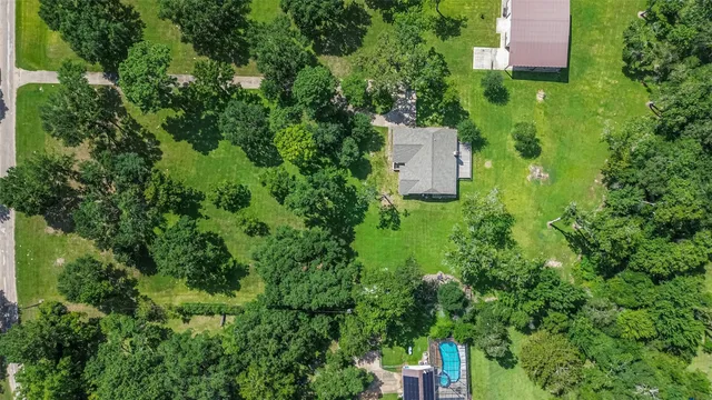 an aerial view of residential house with outdoor space and trees all around