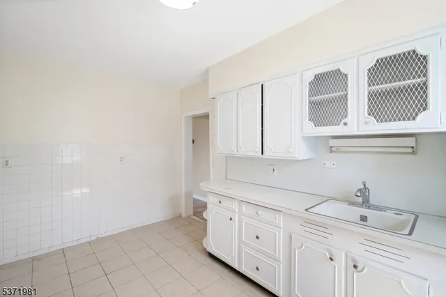 a kitchen with white cabinets and sink