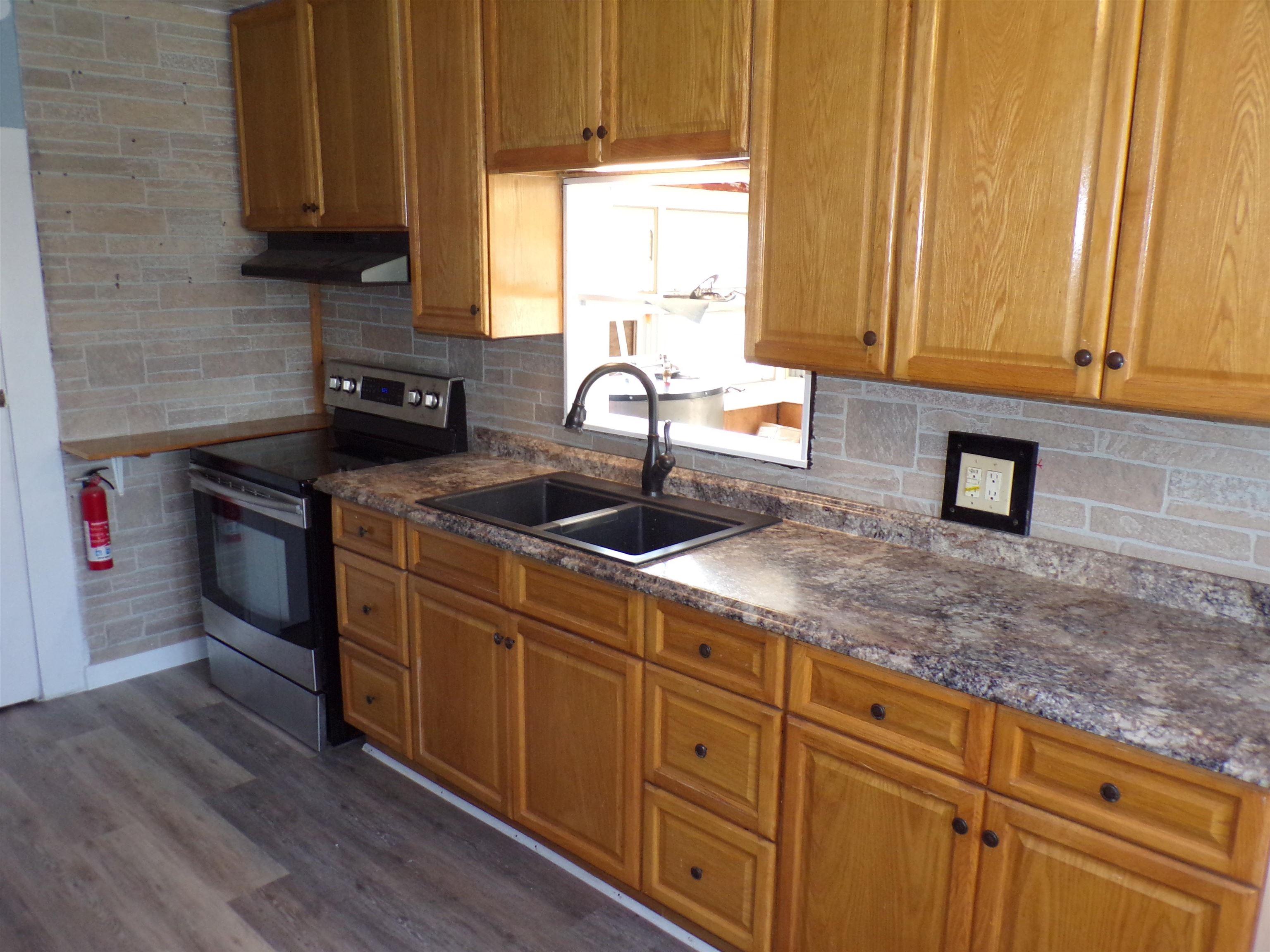 5950 Highway 57 Counce, TN 38326 - Photo 9 of 23 Kitchen featuring stainless steel electric range, decorative backsplash, wood finish cabinetry, dark wood-style flooring, and exhaust hood
