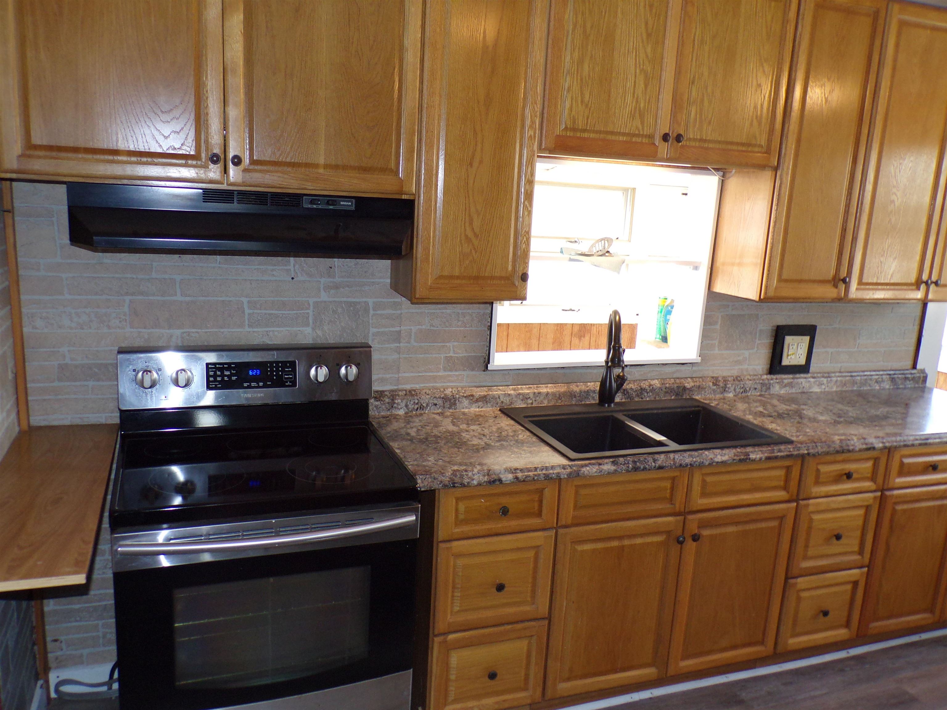 5950 Highway 57 Counce, TN 38326 - Photo 10 of 23 Kitchen featuring stainless steel electric stove, decorative backsplash, wood finish cabinets, and dark wood-type flooring