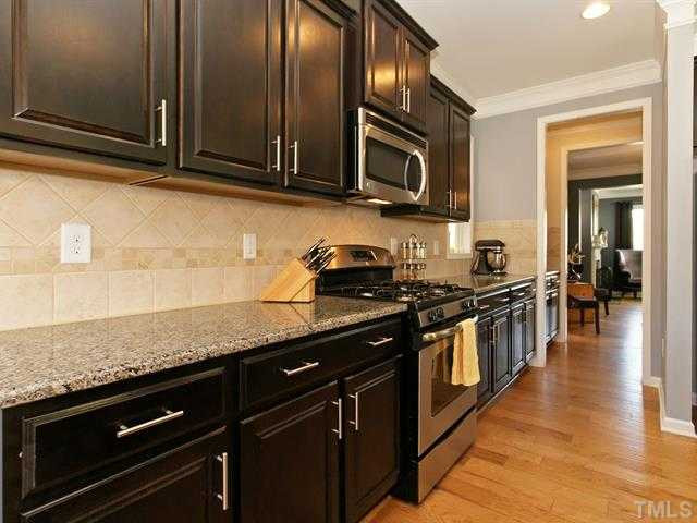 1403 Van Page Boulevard Raleigh, NC 27607 - Photo 9 of 25 Cooking is a delight in the kitchen that offers stainless steel appliances, granite counters, a tile backsplash, and a walk-in pantry. Kitchen