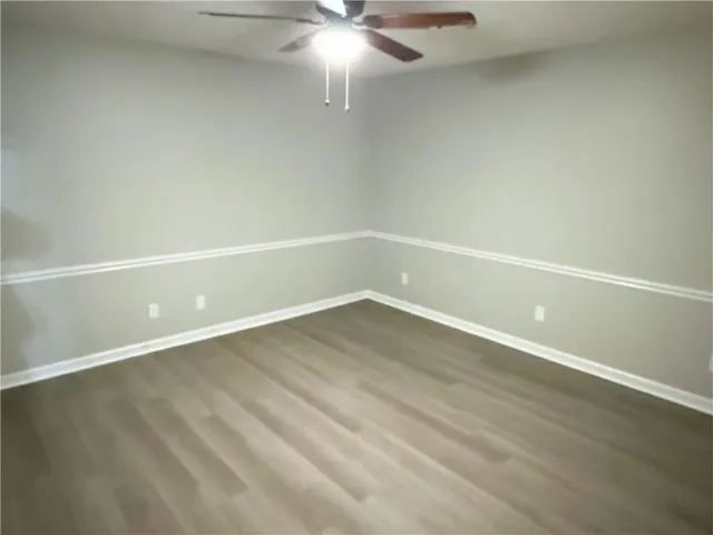 en empty room with wooden floor and fan