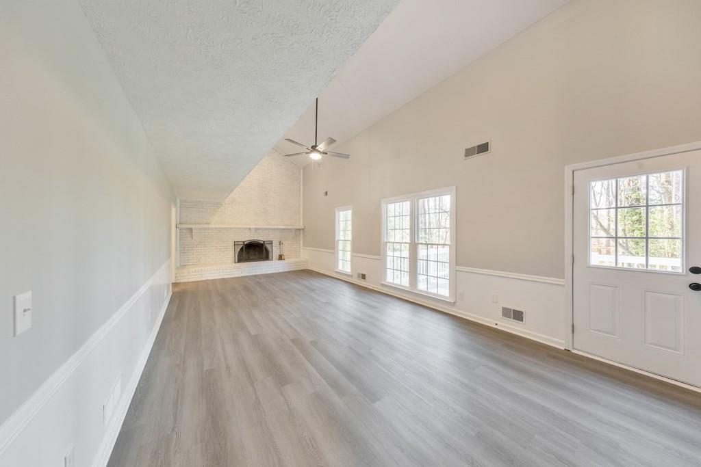 2870 Horseshoe Bend Road Southwest Marietta, GA 30064 - Photo 13 of 37 an empty room with wooden floor chandelier fan and windows