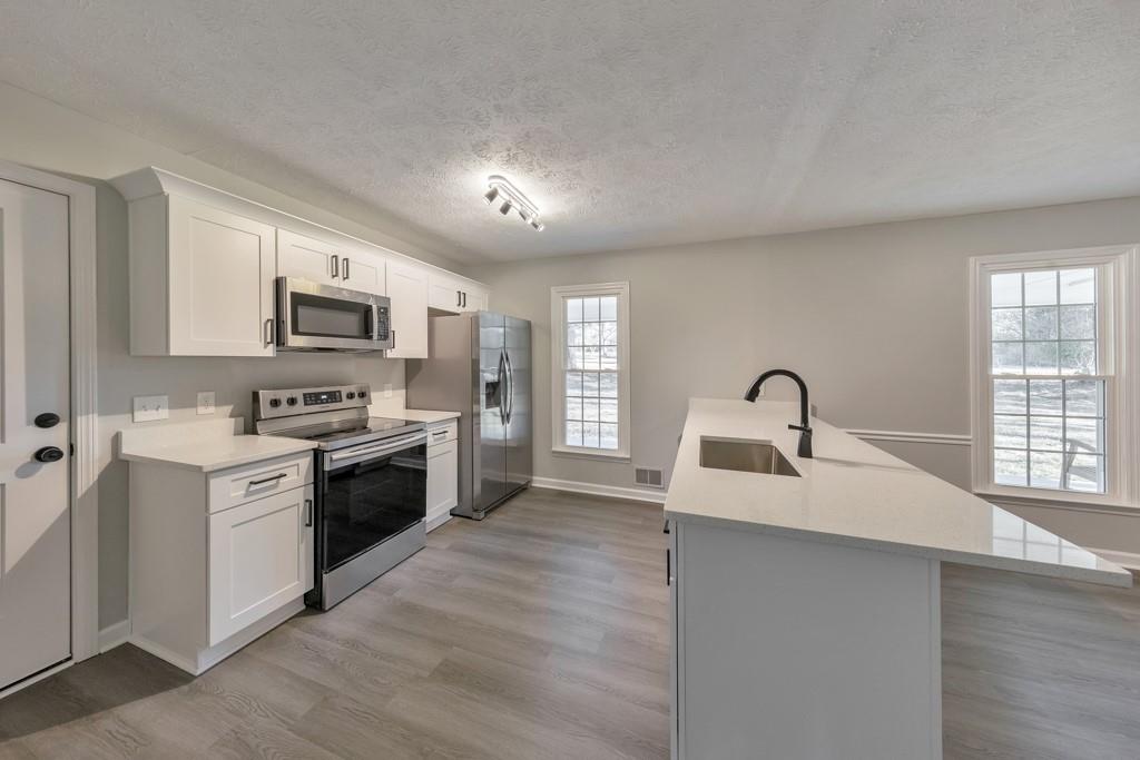 2870 Horseshoe Bend Road Southwest Marietta, GA 30064 - Photo 16 of 37 a large kitchen with stainless steel appliances granite countertop a sink dishwasher a stove and a refrigerator with wooden floor