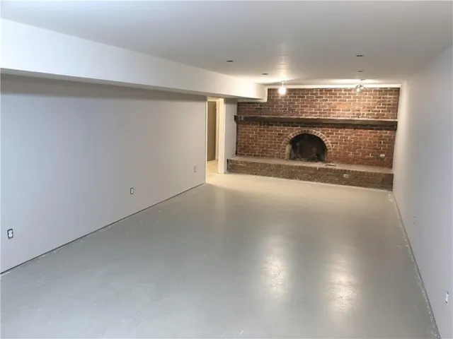 an empty room with a fireplace and a ceiling fan