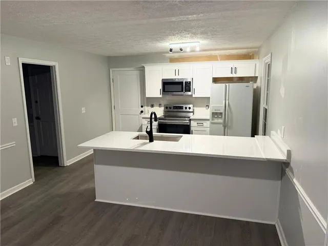 a kitchen with stainless steel appliances a sink a stove a refrigerator and cabinets