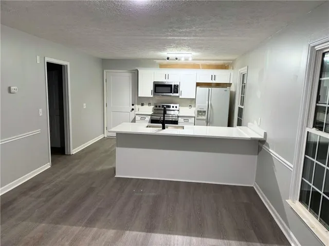 a room with kitchen island wooden floor and stainless steel appliances