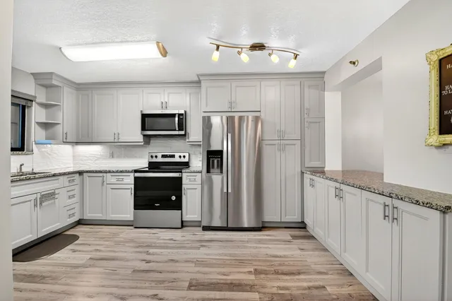 a kitchen with granite countertop a refrigerator stove and microwave