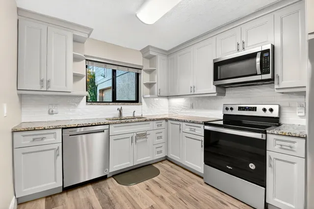 a kitchen with stainless steel appliances granite countertop a stove microwave and sink