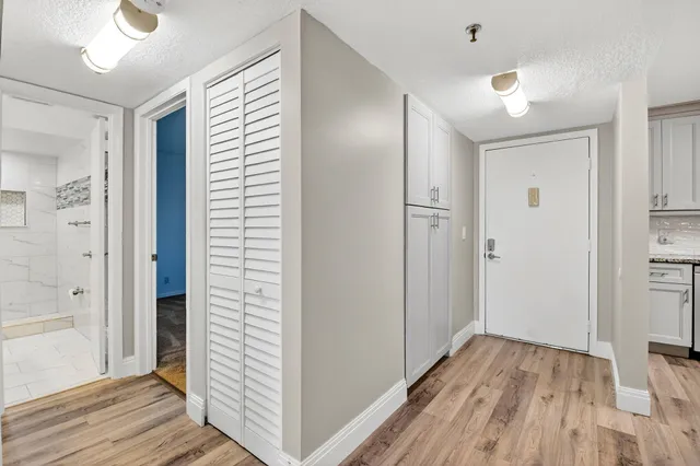 a view of a hallway with wooden floor and closet area