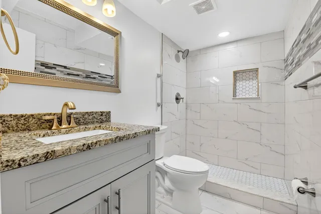 a bathroom with a granite countertop sink a toilet and a mirror