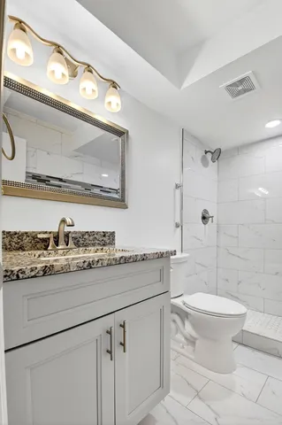 a bathroom with a granite countertop toilet sink and mirror