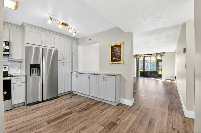 a view of a kitchen with wooden floor electronic appliances and windows