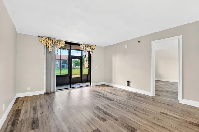 a view of an empty room with wooden floor and a window