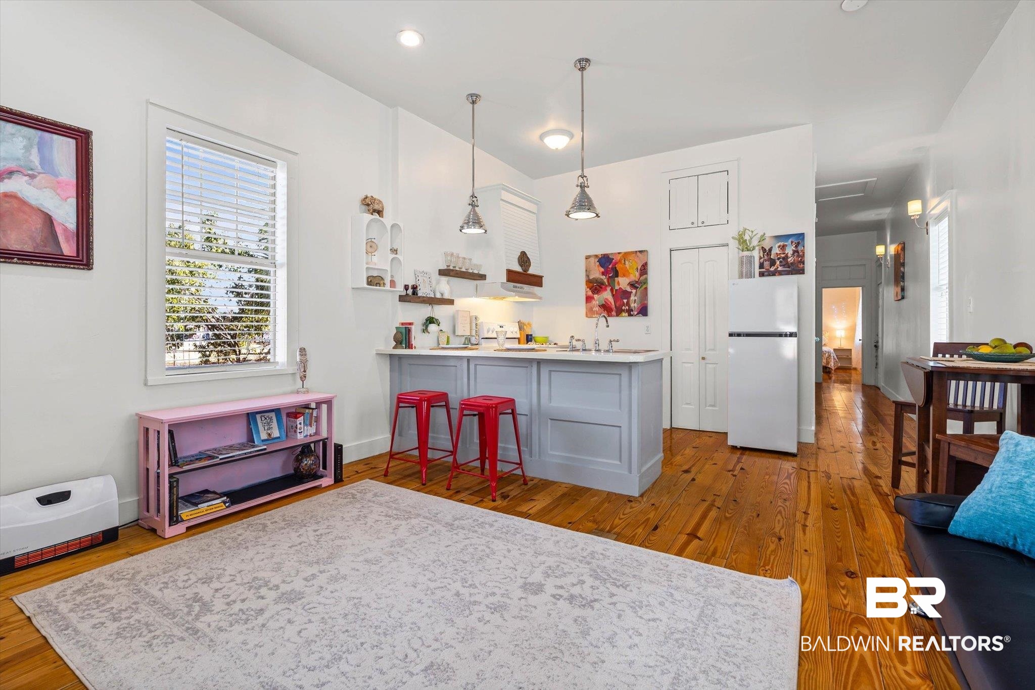 951 Montgomery Street Mobile, AL 36604 - Photo 4 of 22 Open-concept living space featuring wood-finish flooring, recessed lighting, a kitchen island with seating, and a large window providing natural light