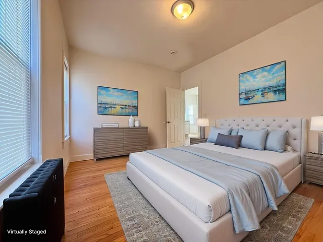 a spacious bedroom with a bed and a painting on the wall