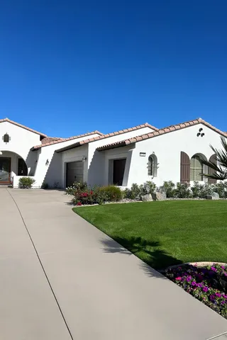 a view of a white house with a big yard and potted plants