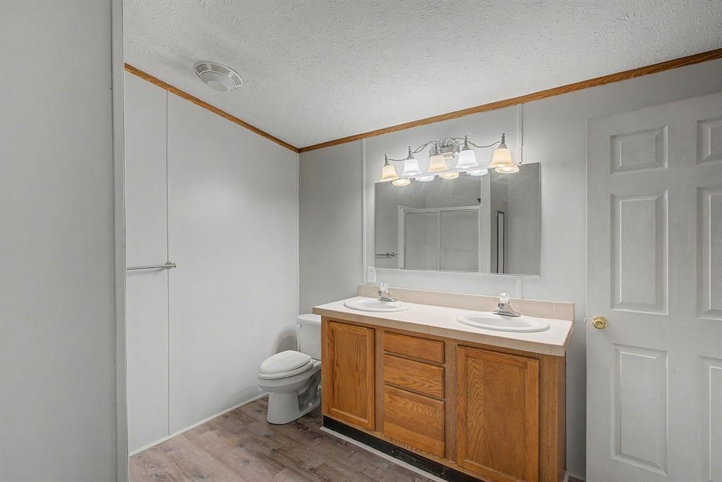 1202 Princeton Road Princeton, LA 71067 - Photo 15 of 19 Full bathroom featuring a wood-finish double vanity with dual undermount sinks, a coordinating mirror, and an overhead multi-bulb light fixture