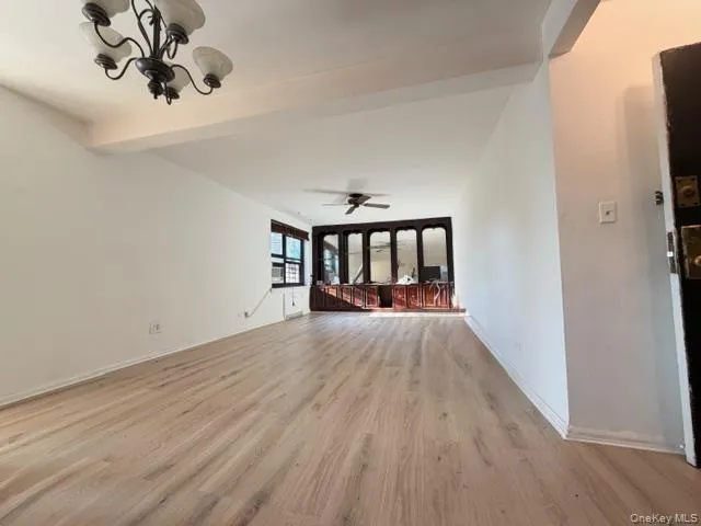 a view of an empty room with window and wooden floor