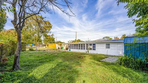 a view of a house with a big yard plants and large trees