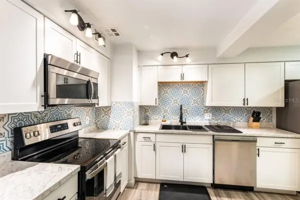 a kitchen with stainless steel appliances a sink stove and cabinets