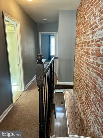 a view of a hallway with wooden floor and stairs