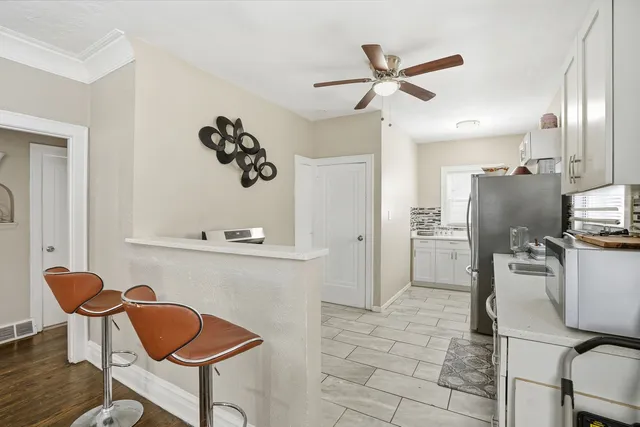 a kitchen with stainless steel appliances granite countertop a dining table chairs and a refrigerator