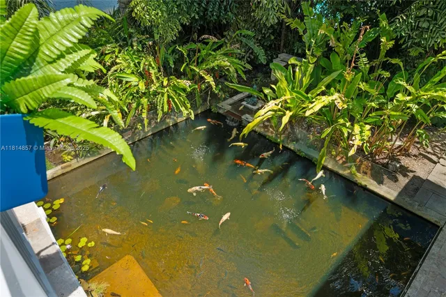 a view of a lake with lawn chairs and large trees