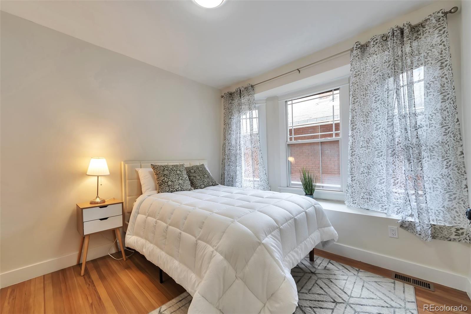 1417 Monroe Street Denver, CO 80206 - Photo 23 of 43 a bedroom with a bed and wooden floor