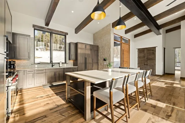 a dining hall with stainless steel appliances kitchen island granite countertop a table chairs and a refrigerator