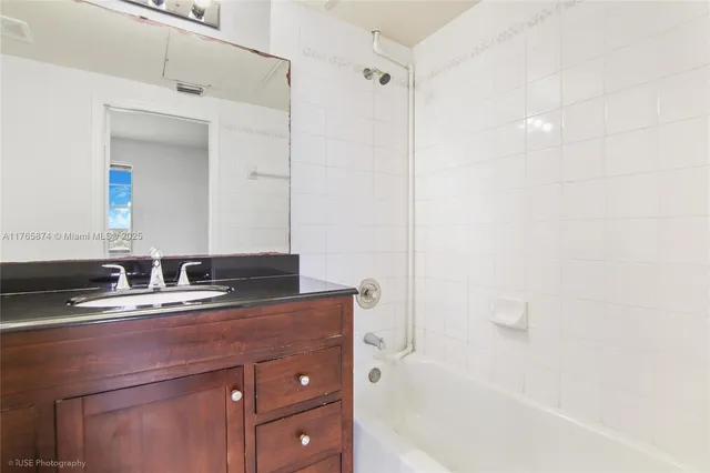 a bathroom with a granite countertop sink mirror and a bathtub