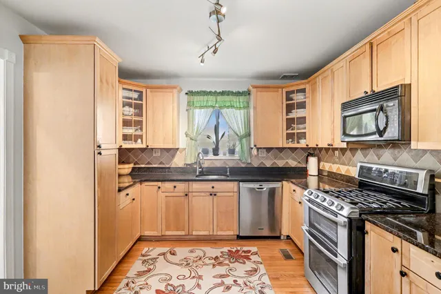 a kitchen with stainless steel appliances granite countertop a stove a sink and a microwave