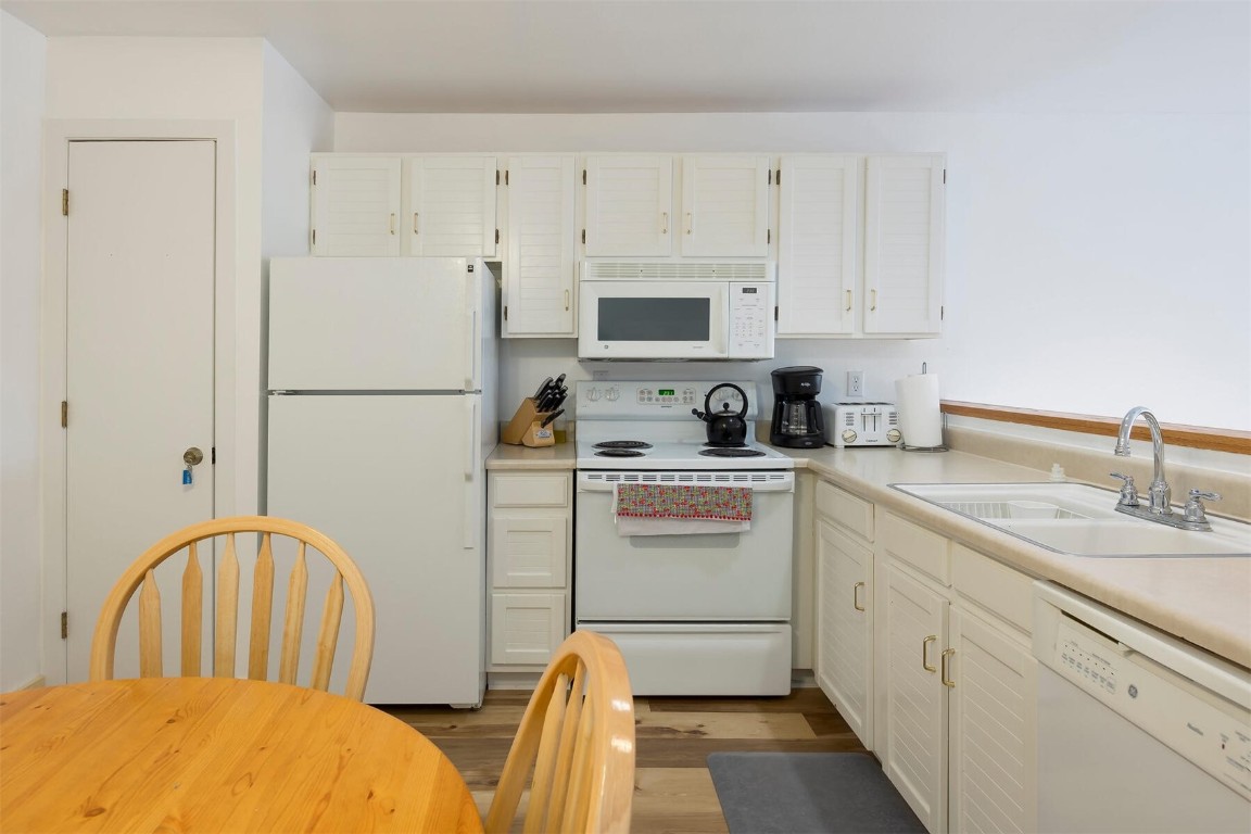 10000 Ryan Gulch Road, Unit G105 Silverthorne, CO 80498 - Photo 7 of 37 Kitchen featuring white appliances, white cabinets, and light countertops